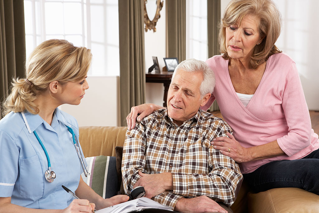 An Elderly Man Being Comforted By A Relative While Talking To His Care Giver