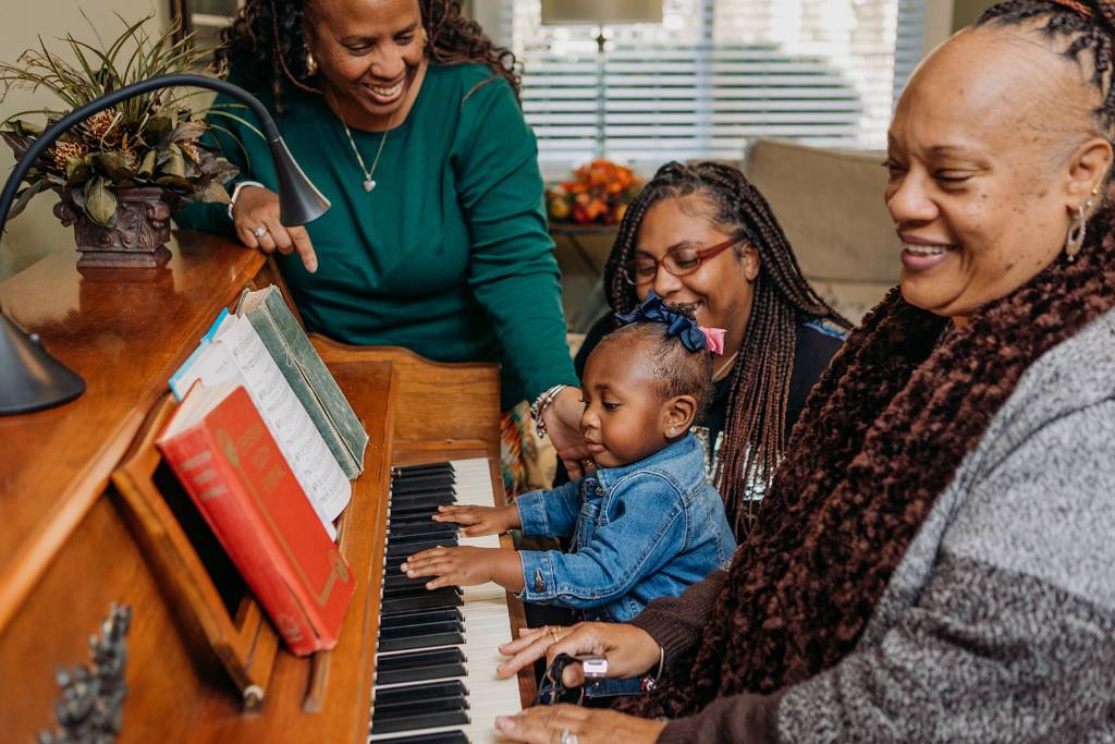 Three Black Women Watching A Child Play The Piano