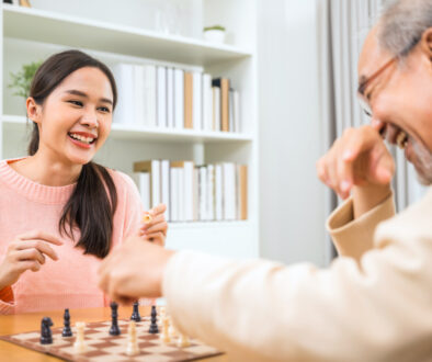 Asian Woman Playing Chess With Elderly Man As Part of Summer Volunteer Programs
