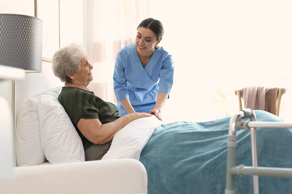 A Care Worker Adjusting The Bed Sheets For An Elderly Hospice Patient Difference Between Inpatient Hospice vs. Outpatient Hospice.