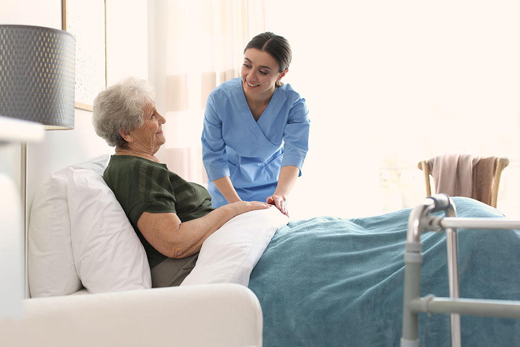 A Care Worker Adjusting The Bed Sheets For An Elderly Hospice Patient Difference Between Inpatient Hospice vs. Outpatient Hospice.