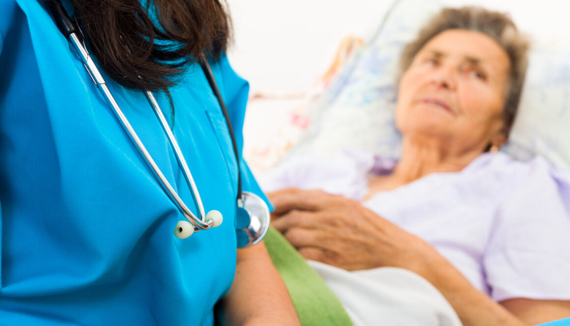 Closeup of a Nurse With an Elderly Patient in the Background How Does Hospice Work for Dementia Patients