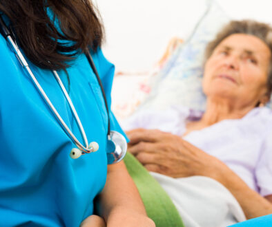 Closeup of a Nurse With an Elderly Patient in the Background How Does Hospice Work for Dementia Patients