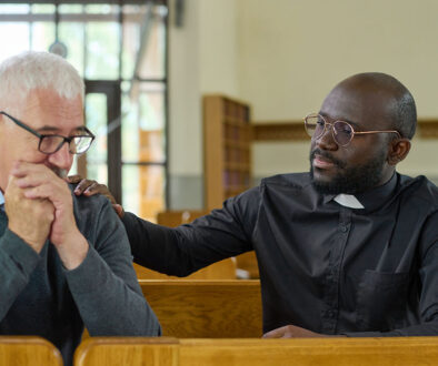 An African American Pastor With His Hand on an Older White Man’s Shoulder Providing Comfort Hospice Spiritual Care