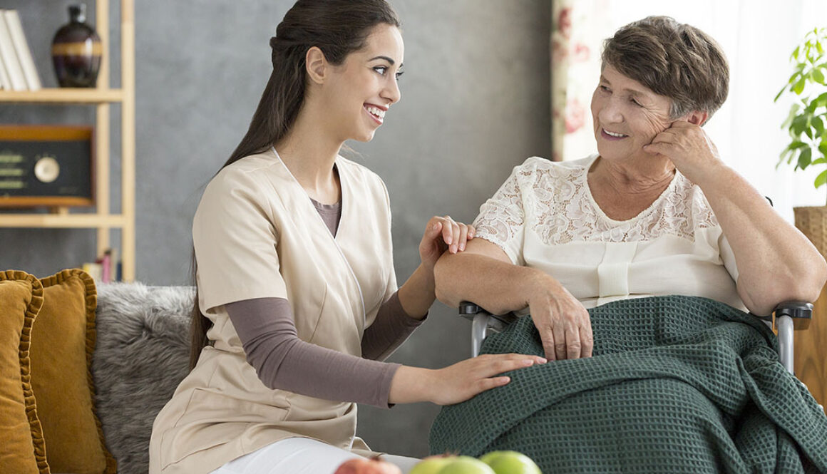 A Young Volunteering Caregiver Sitting Beside a Smiling Elderly Woman in a Wheelchair Is Hospice Volunteering Clinical