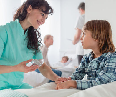 A Nurse Smiling While Giving Medication to a Child Sitting in a Bed Holistic Pediatric Hospice Care