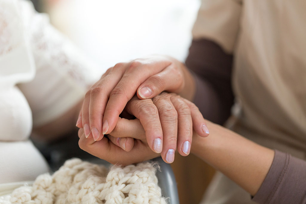 Close Up Of A Hospice Nurse Holding A Patient's Hand Providing Emotional Support For Hospice Patients