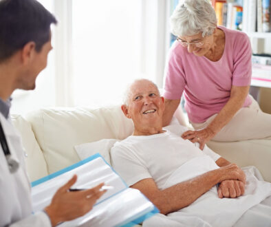 A Doctor Talking To A Senior Man Sitting On A Couch Beside A Senior Woman Hospice Care In Assisted Living